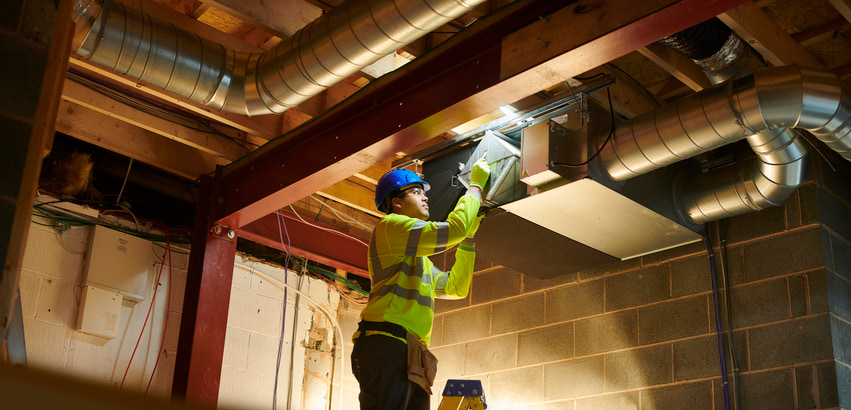 Technician cleaning industrial ventilation ducts. The importance of cleaning ducts during flu season