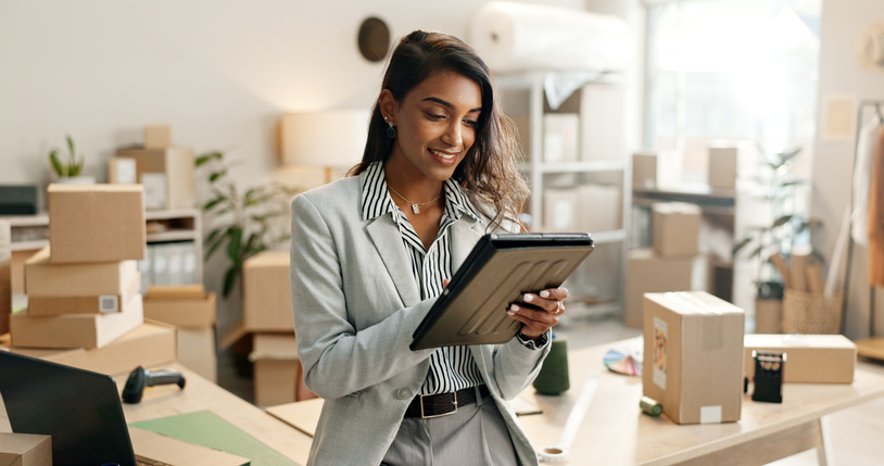 woman in office surrounded by boxes on her ipad