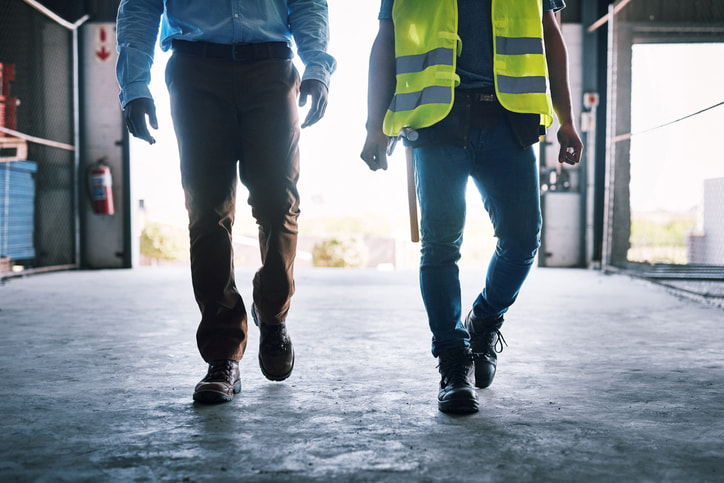 Office worker and field worker walking into warehouse